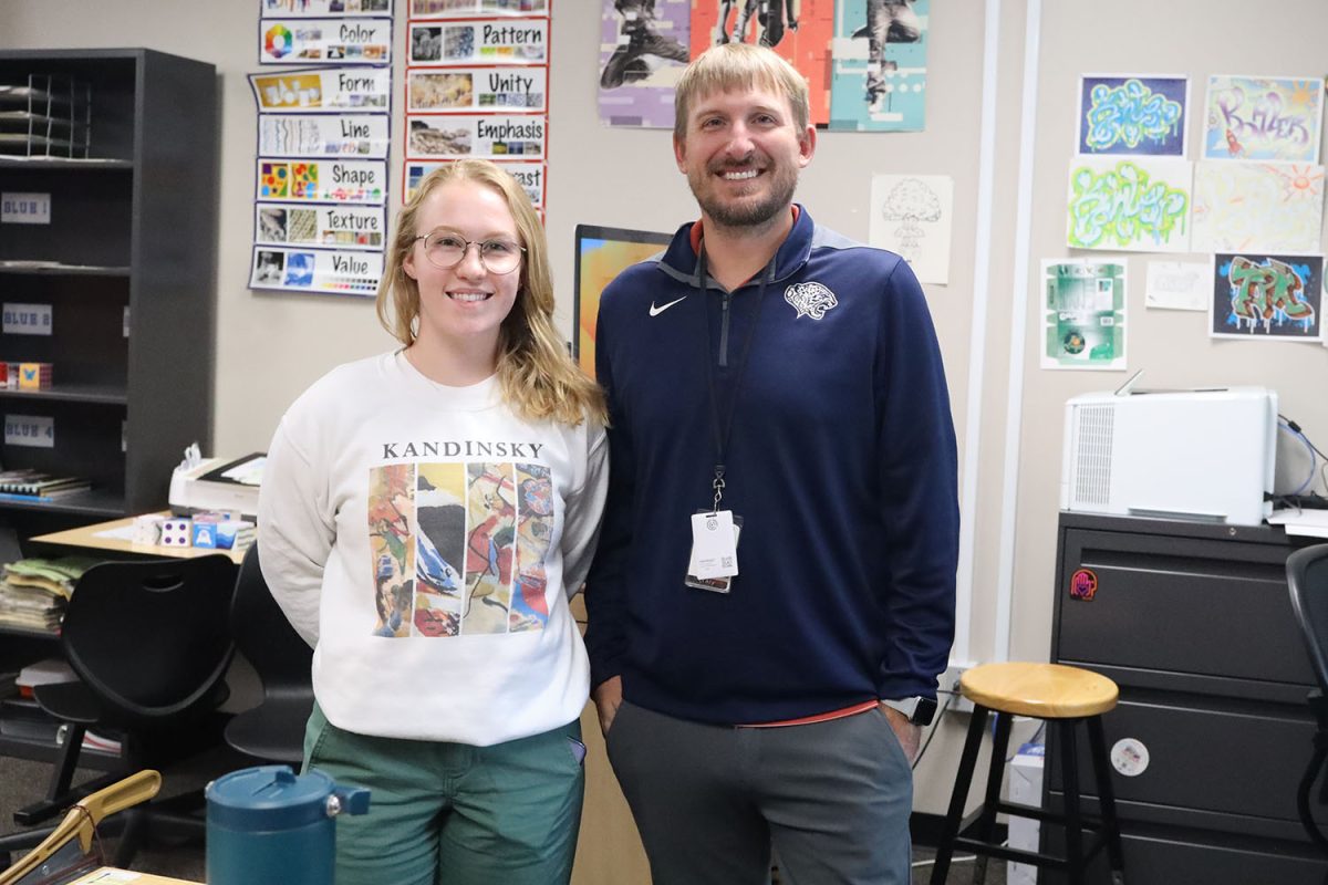 Together, art teacher Samantha MacAuley and Travis Kohler, stand in their shared learning space. MacAuley uses Kohler’s room for Graphic Design Fundamentals when she isn’t teaching Art I and Sculpture. “Art has so many material options made available to them when creating their art while Graphic Design is limited to technology,” MacAuley said. “It also has the ability to create so many different and interesting things.”