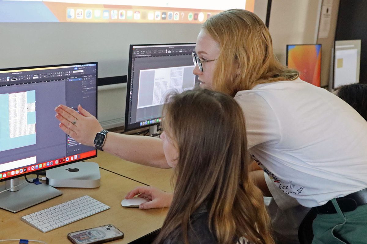 Peering over the shoulder of her student, art teacher Samantha MacAuley assists freshman Molly Gilmore on her project in Graphic Design Monday, Nov. 6. “Juggling multiple projects in Graphic Design can be very challenging,” Gilmore said. “Ms. MacAuley is really helpful whenever I’m confused and need help with something.”