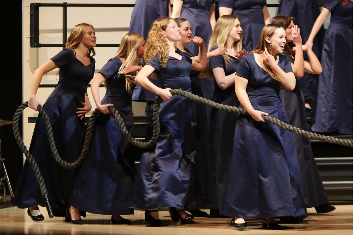 Preparing for a game of tug-of-war, a group of girls look across the stage. 