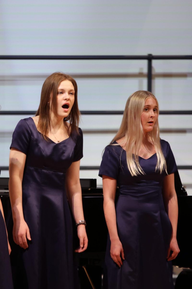 Looking out at the audience, seniors Caroline Alley and Lanie DeWitte sing with Jag Singers.