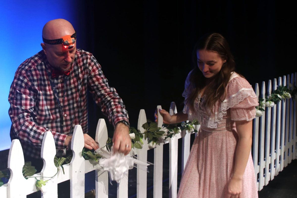 Drama director Jon Copeland works with junior Allyson Makalous to fix the flowers on the set.