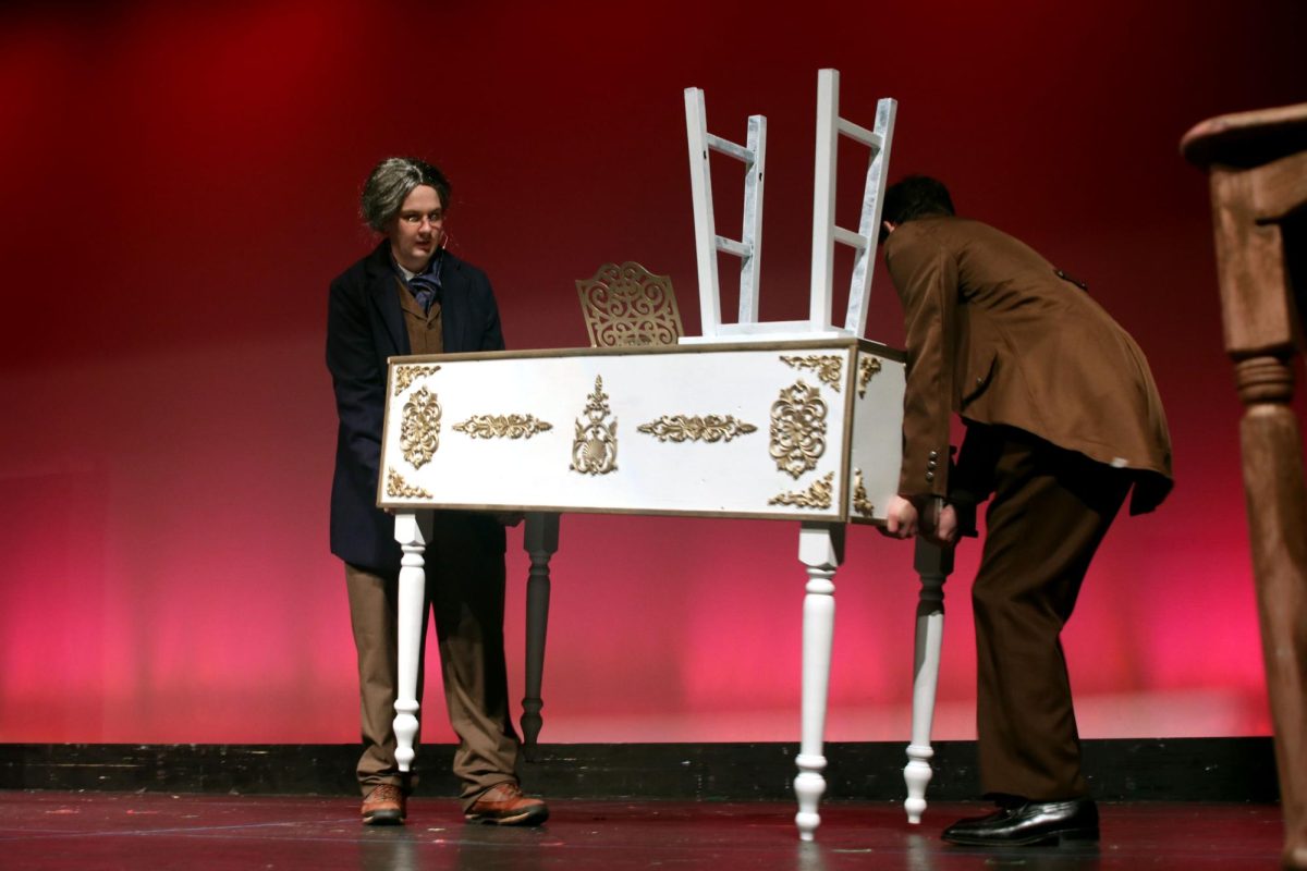 Senior Nate Garner and junior Kai McGarry work together to carry a prop piano on stage.