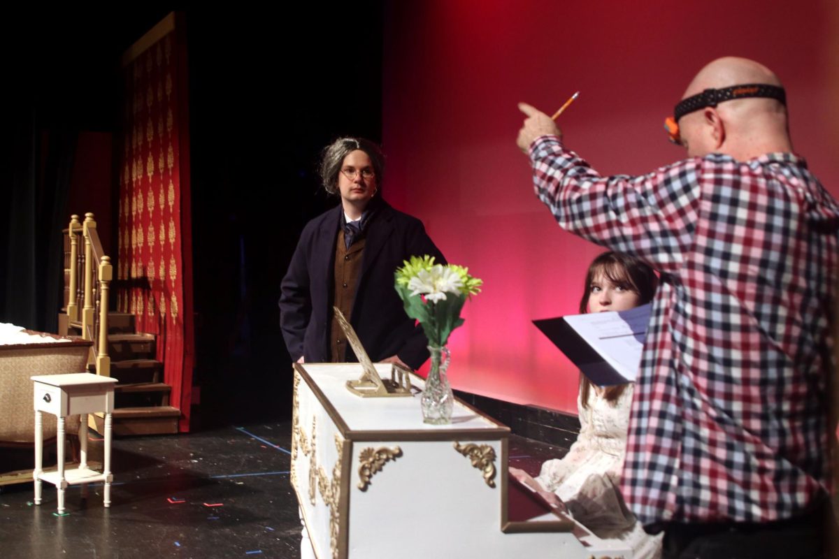 Seniors Nate Garner, Kaelyn Russel, and drama director Jon Copeland discuss which set pieces need to be on the stage for the scene they are running. 