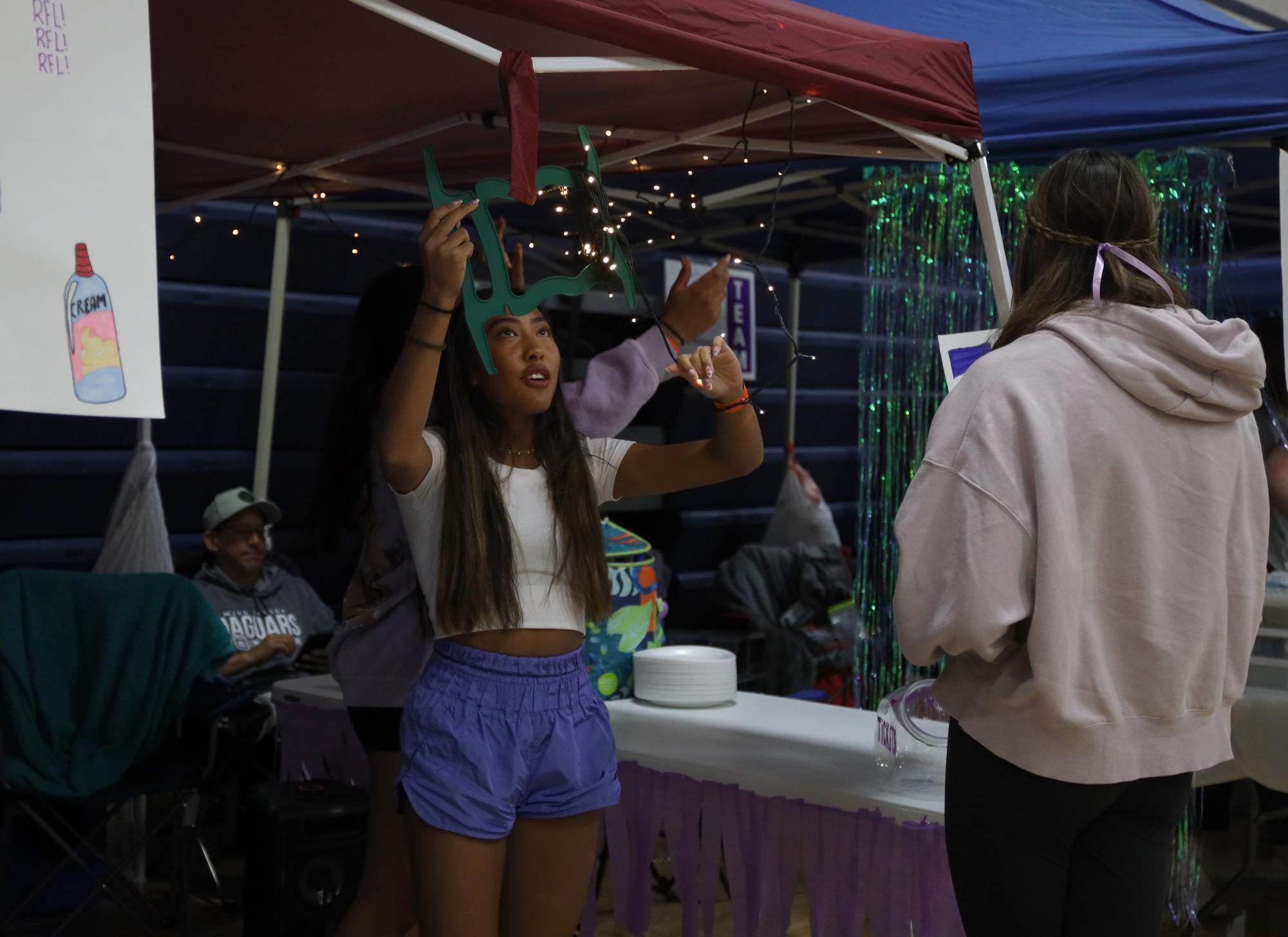 Decorating her “Pie in the Face” booth by hanging lights, freshman Alycia Manirad prepares for Relay for Life to begin. 