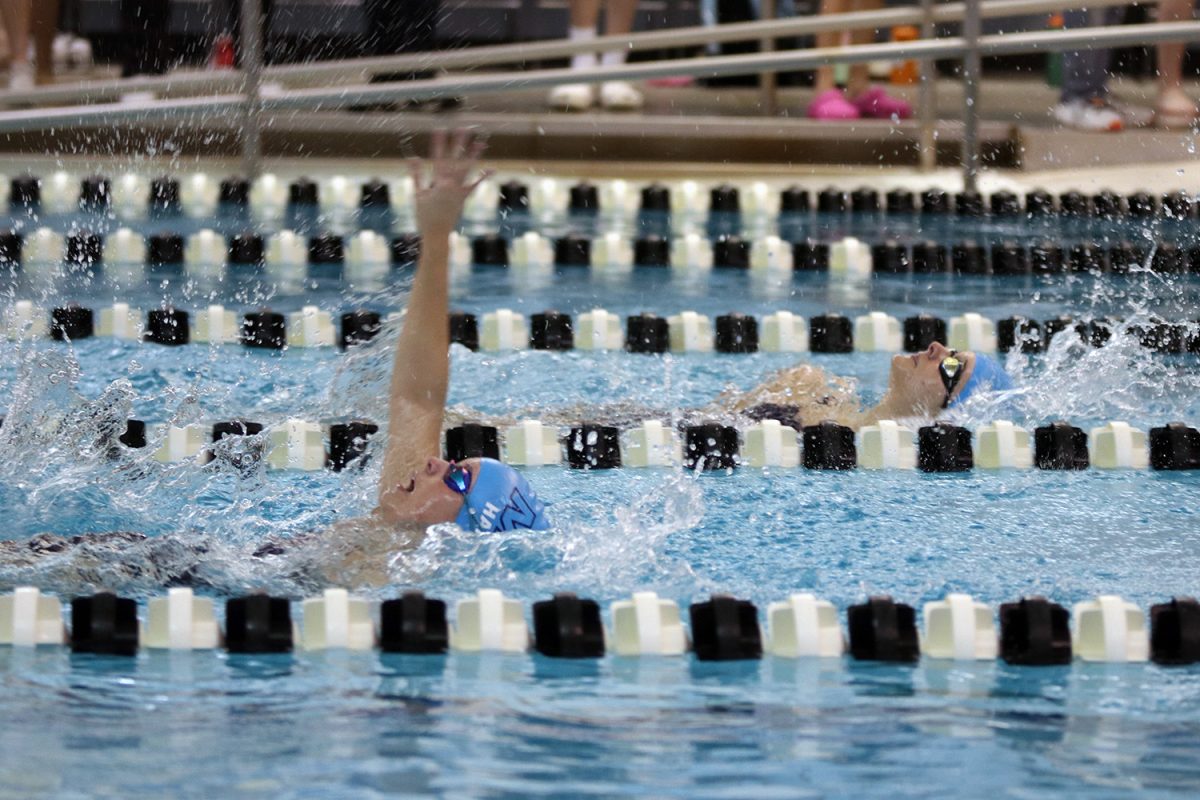 Almost in sync, sophomores Abby Haney and Mackenzie Clifton race through their 100 yard backstroke.