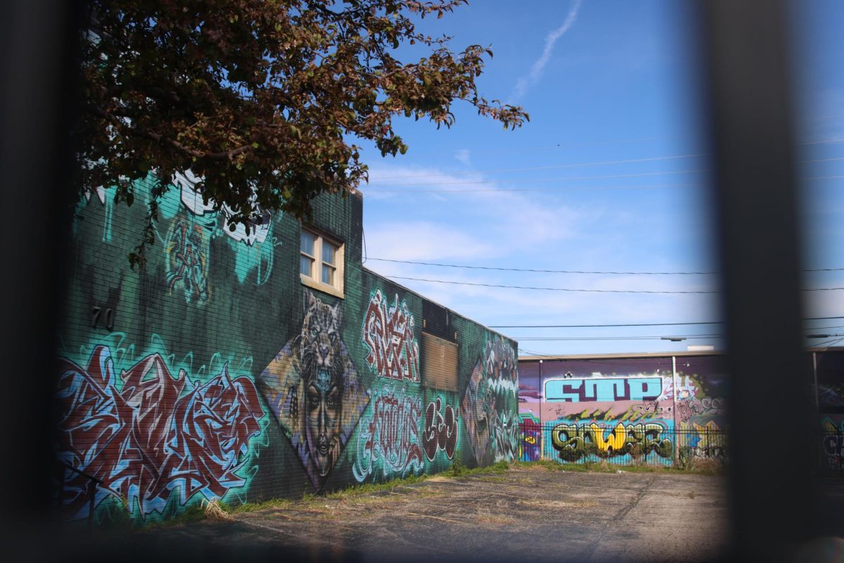 Various artists contribute to decorating the walls of an empty parking lot.