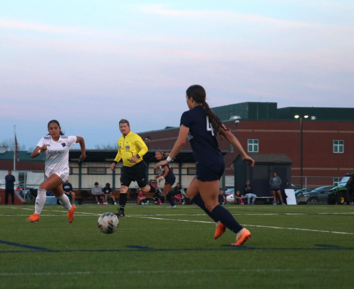 Kicking the ball towards her teammates, junior Lauren Welch runs to beat the opponent 