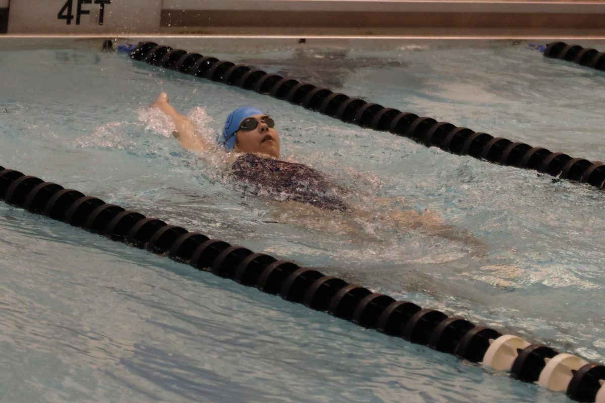 Focusing on her backstroke, freshman Lydia Riek swims down the lane to finish her heat.