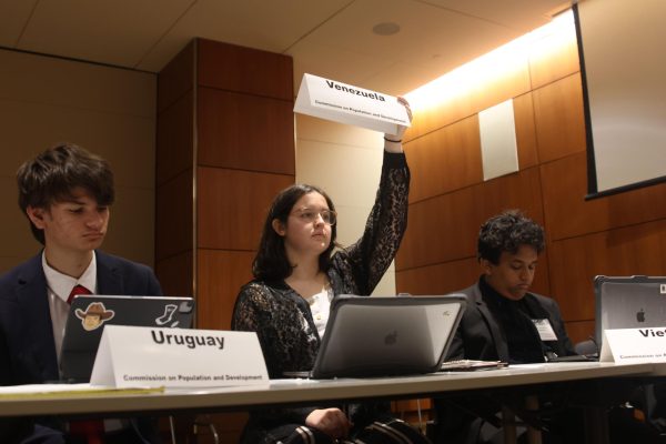 Representing Venezuela, sophomore Quinlyn Peters raises her placard to speak at the conference Wednesday, April 3.