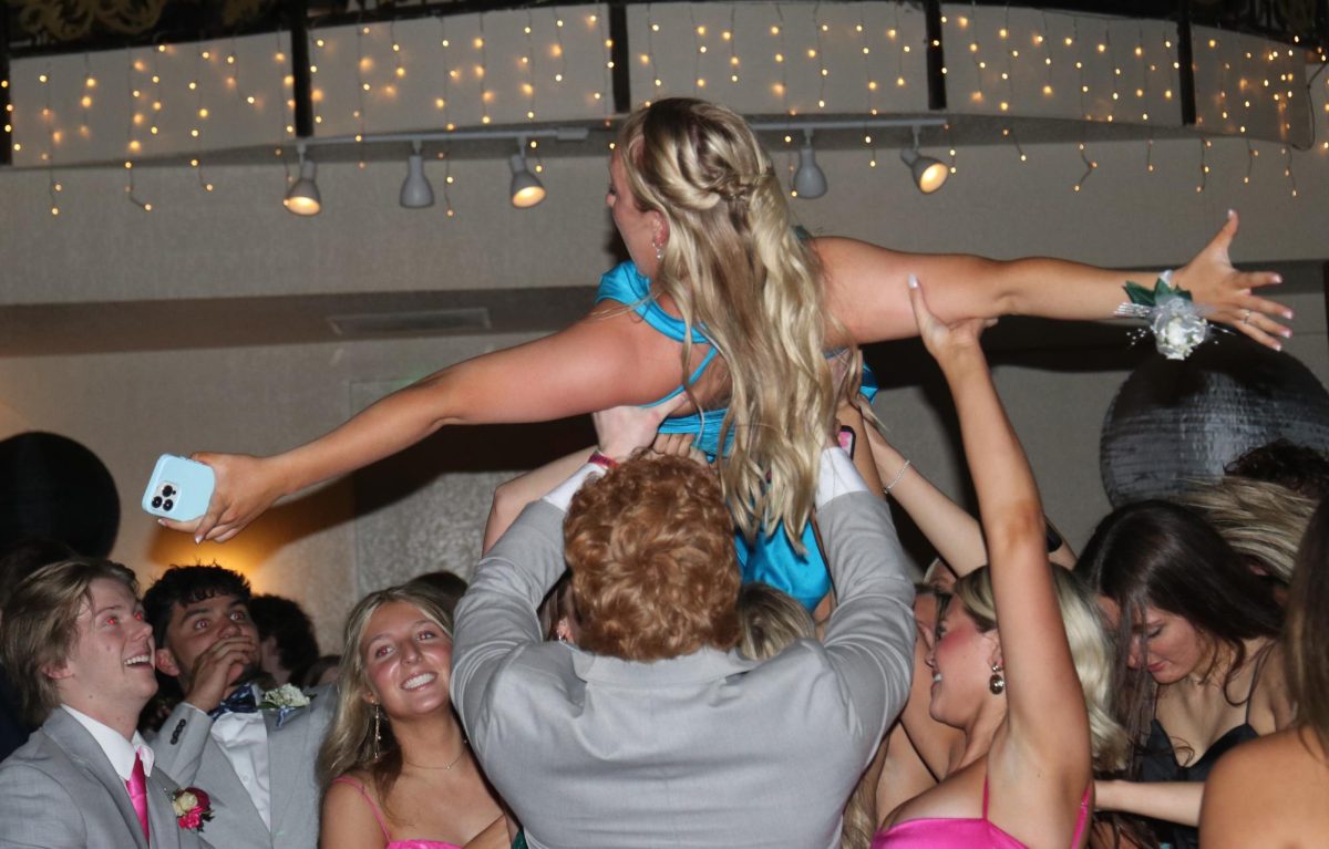 Spreading her arms, senior Danika Dulitz gets lifted into the air by her friends.