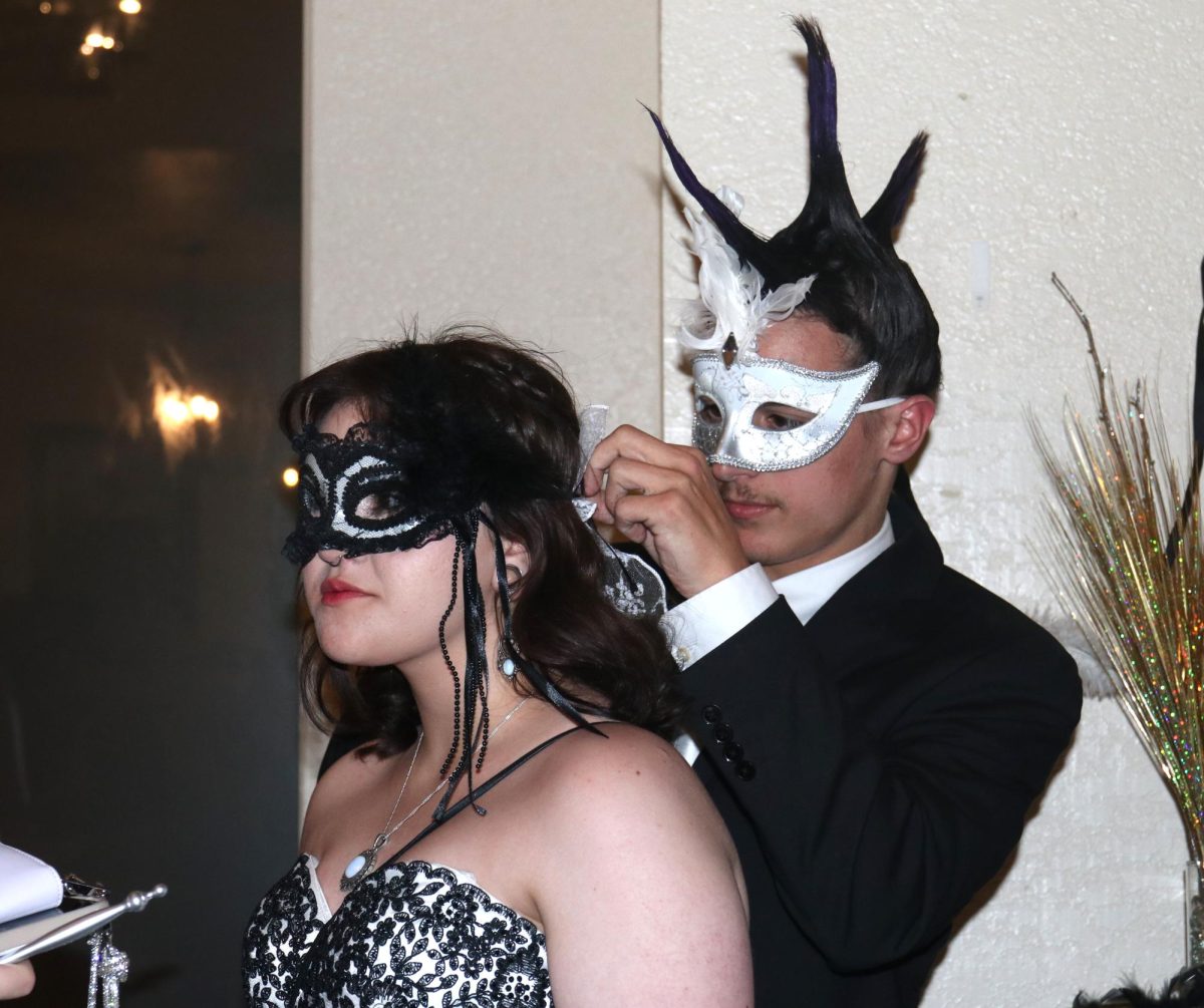 Senior Trent Richardson helps junior Nevaeh Lammons fix the bow on her hair before going onto the dance floor.