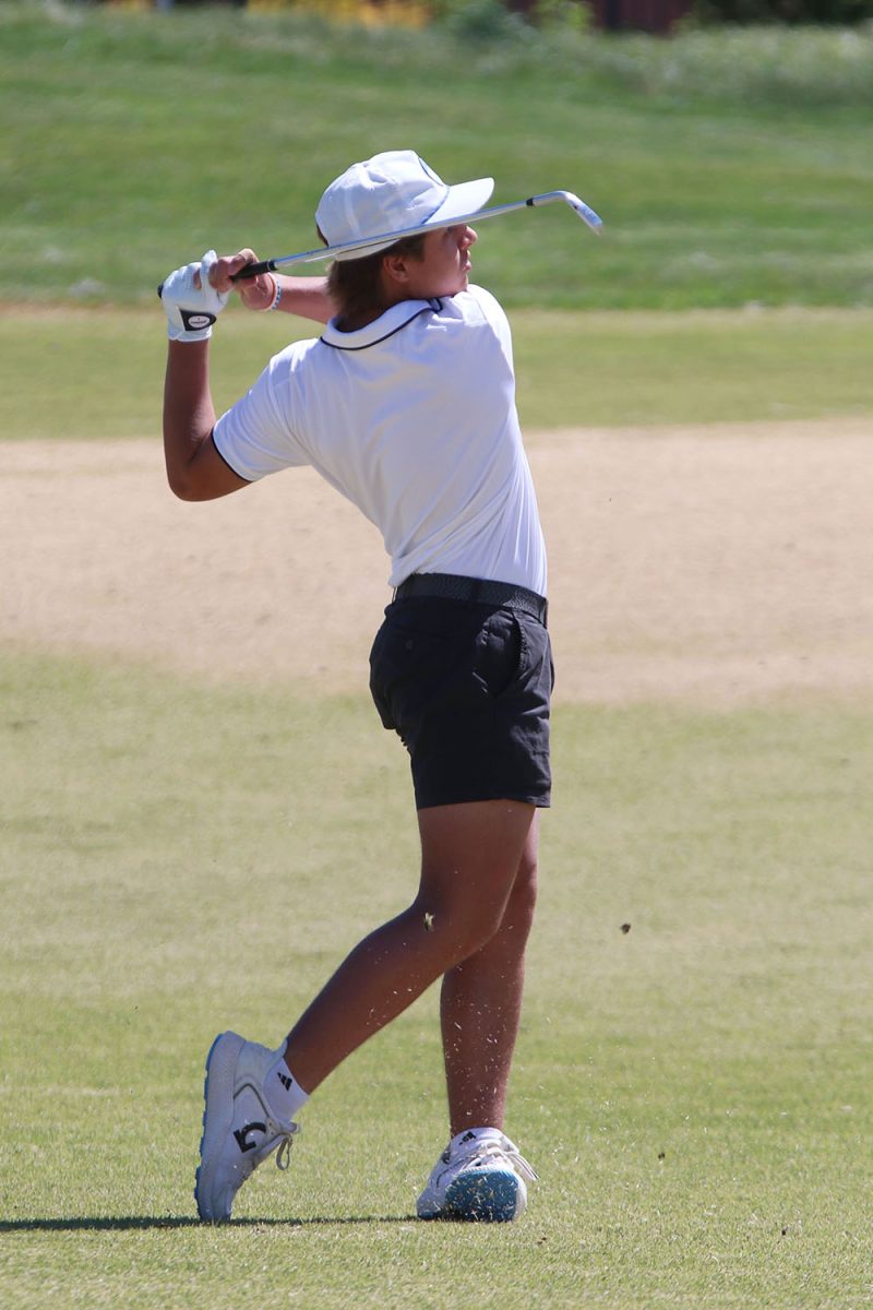 Standing in the fairway, junior Jackson Sprecker finishes his swing. 
