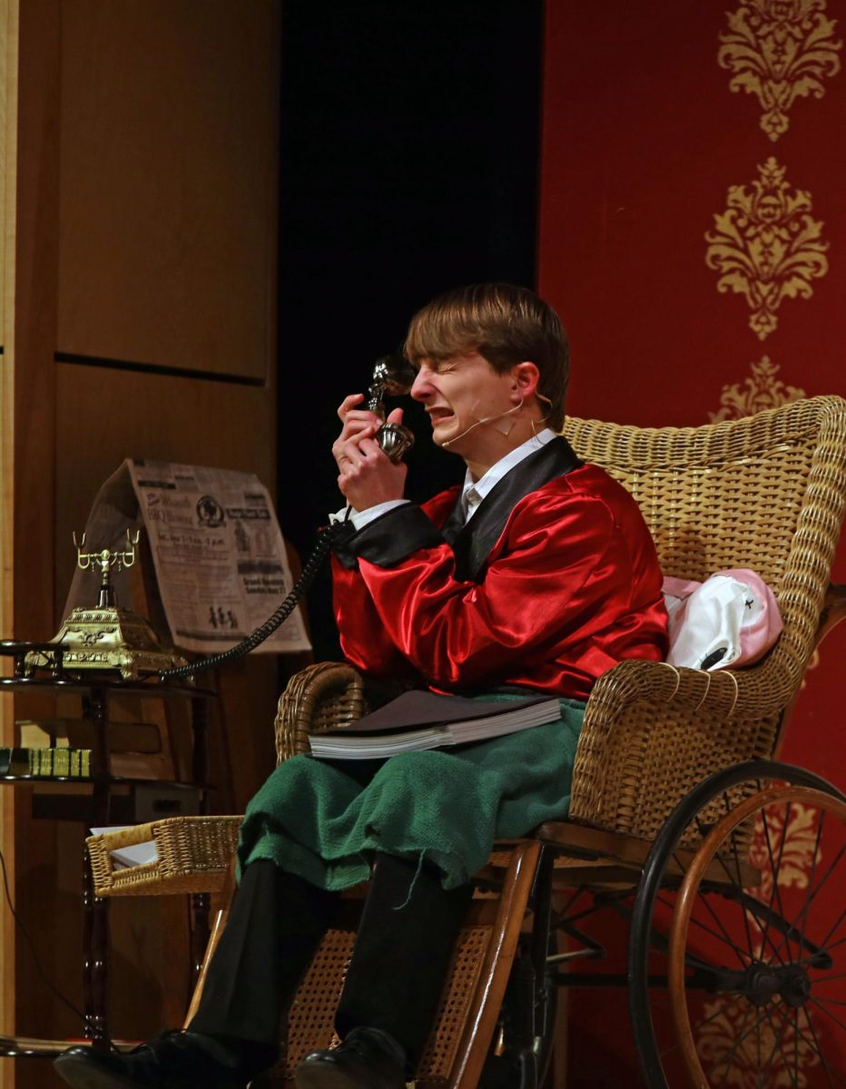 A frustrated expression on his face, Mr. Whiteside, played by sophomore Drew Cormany, holds the telephone up to his ear. 