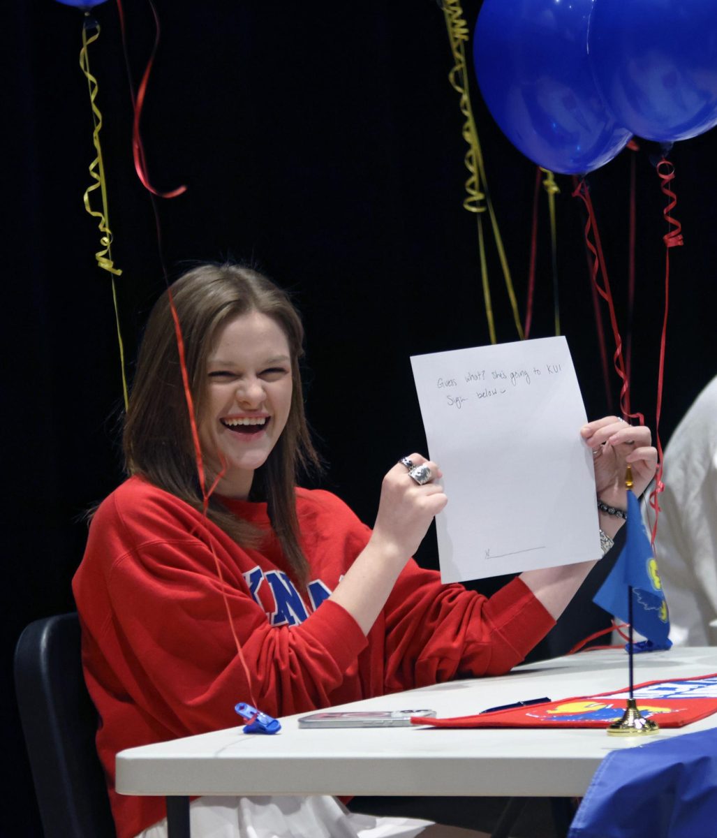 Laughing, senior Caroline Alley holds up her paper to "sign."