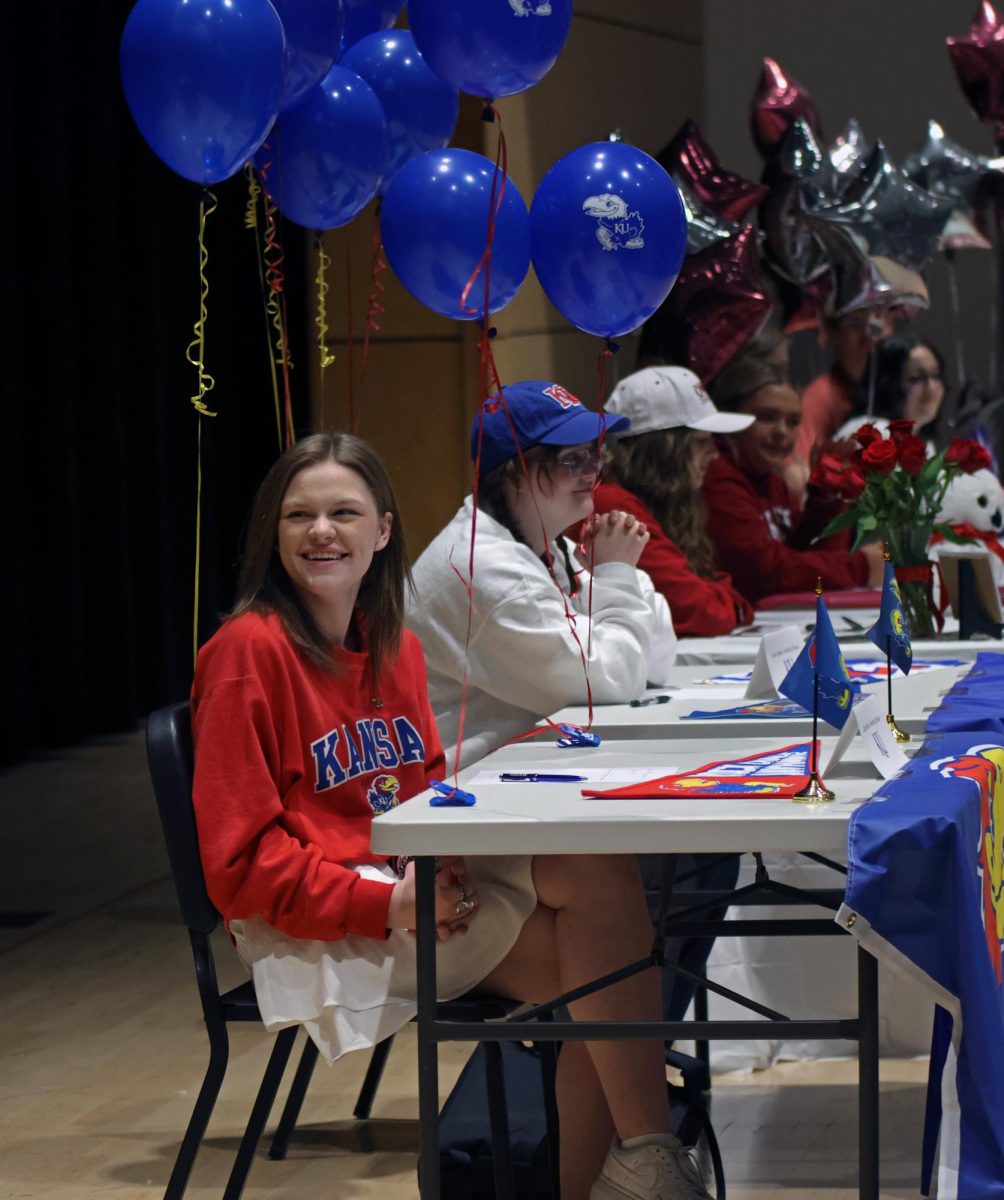 Senior Caroline Alley smiles as choir teacher Jessie Reimer gives a speech about her commitment to KU to continue her music career.