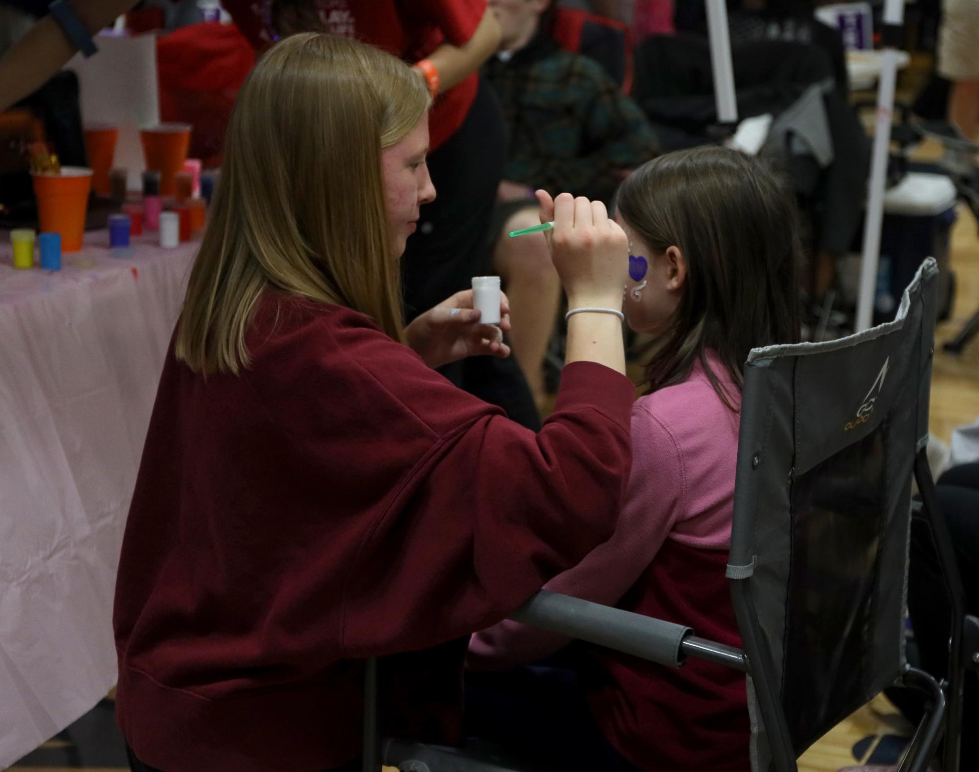 While working her booth, junior Laura Hickman paints a heart on a kids face.