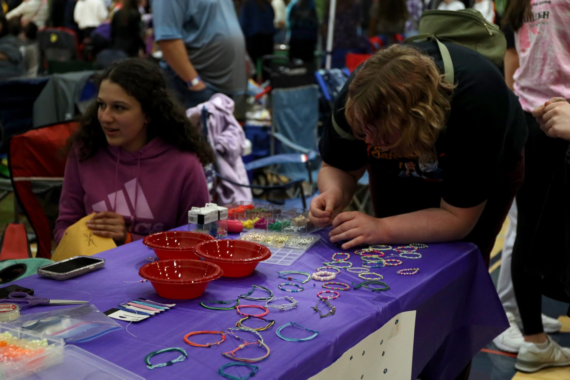 Beading her string, the relay participant makes a bracelet at the friendship bracelet booth. 