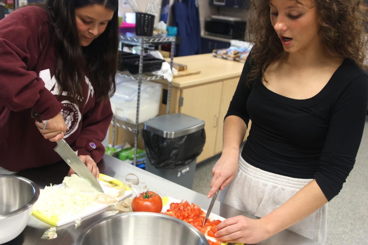 Taking the necessary precautions, juniors Celeste White and Aislyn Wittmer explain how to dice the vegetables.