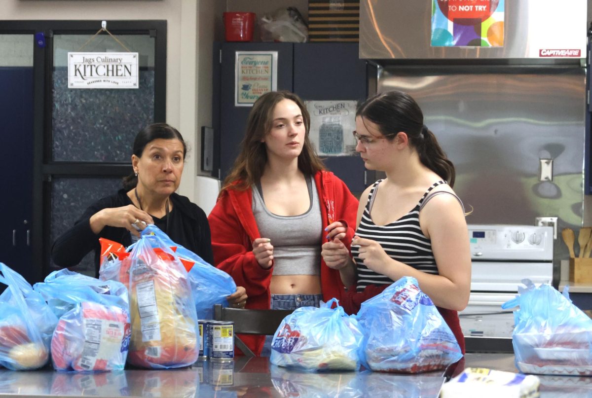 Getting all of the food ready for their meal, seniors Bridgit Duffin and Olivia Peters help SNHS sponsor Edith Paredes unpack the ingredients.