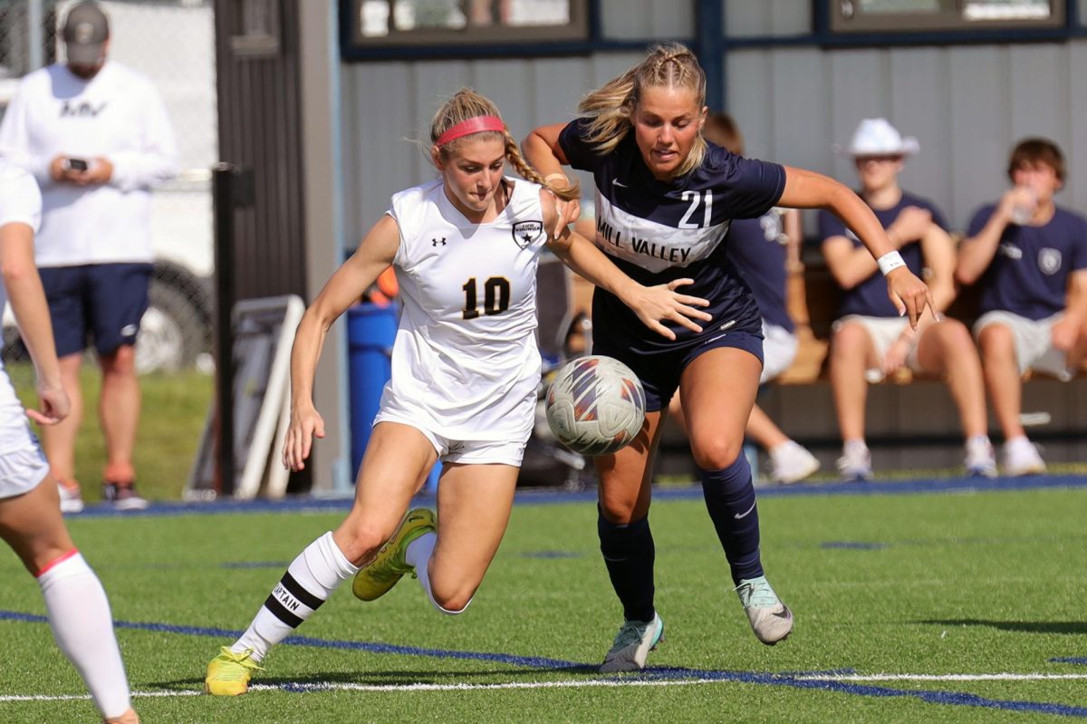 Looking down at the ball, junior Caroline Hooper attempts to take the ball from her opponent.