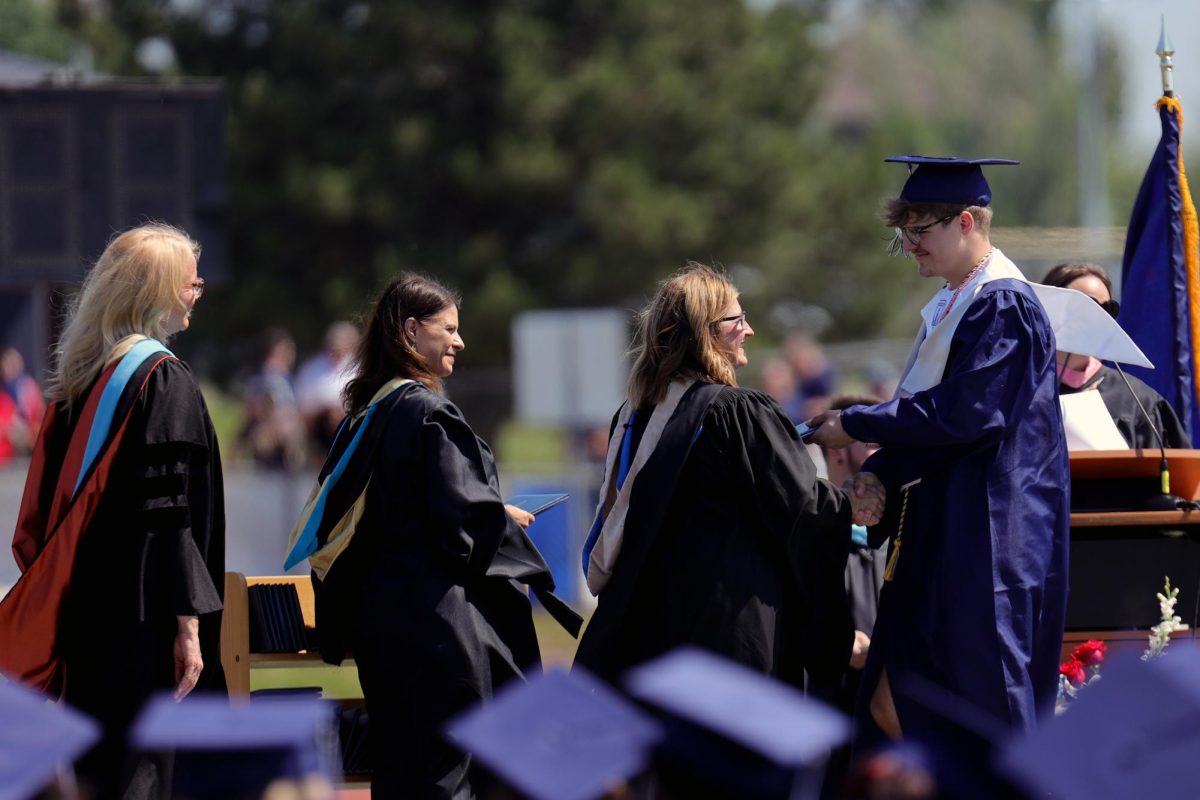 Shaking School Board Vice President Stephanie Makalous's hand, graduate Blake Powers receives his diploma.