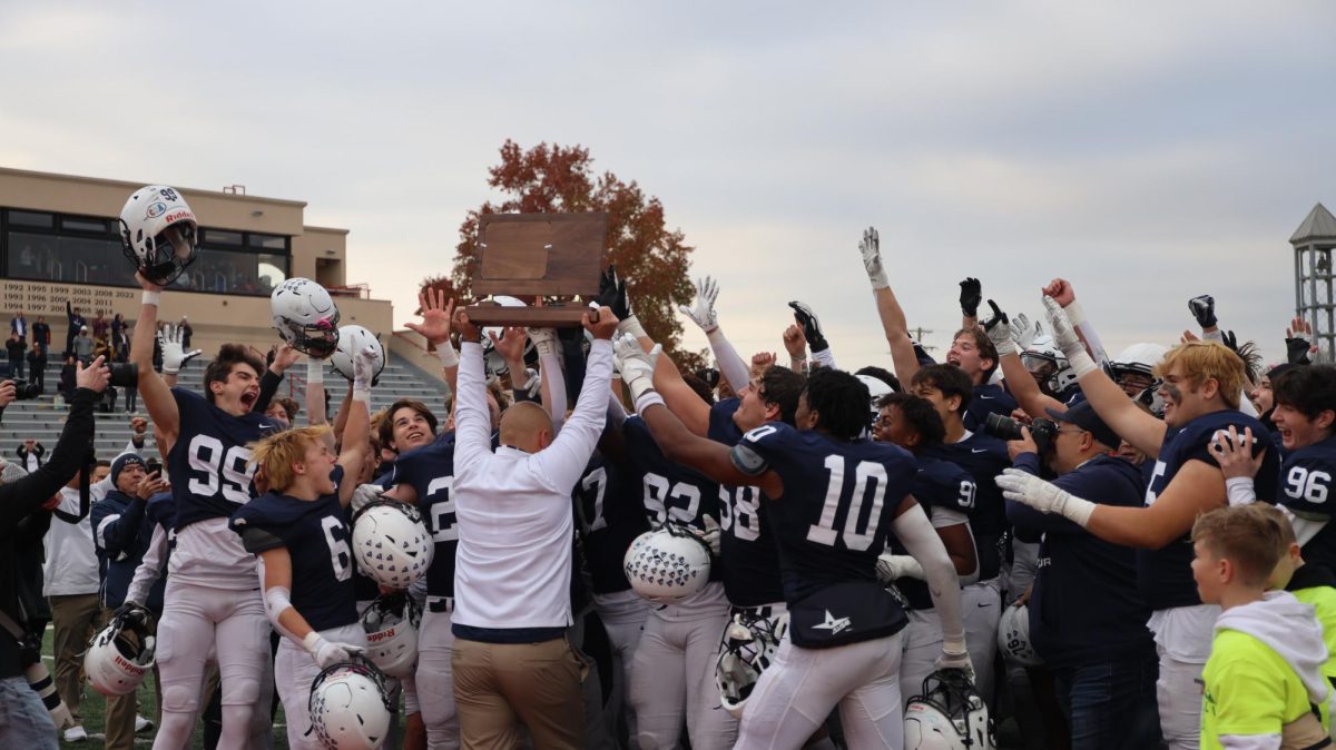 The team celebrates the win while head coach Joel Applebee holds up the 5A championship trophy beating Kapaun 62-37 Saturday Saturday, Nov. 25 2023.  The football team has won five consecutive state titles.  