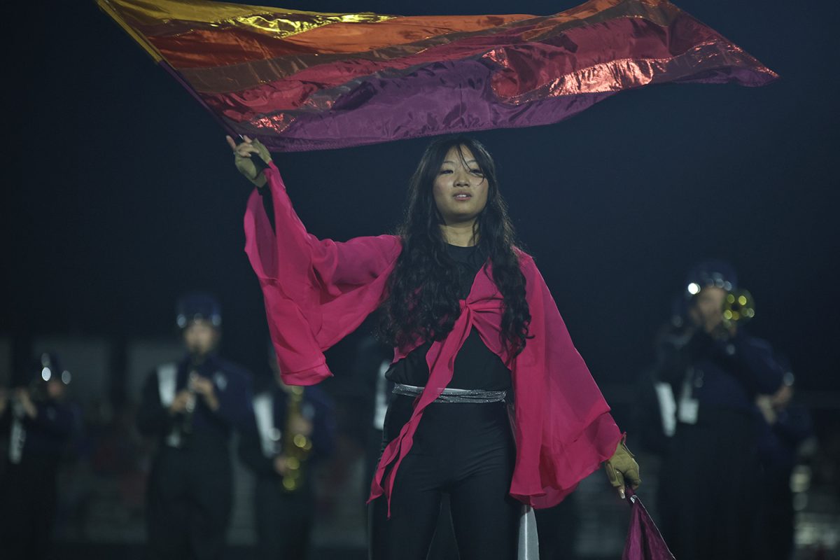 Waving a colorful flag, senior Olivia Thatlor moves to the beat of the band.