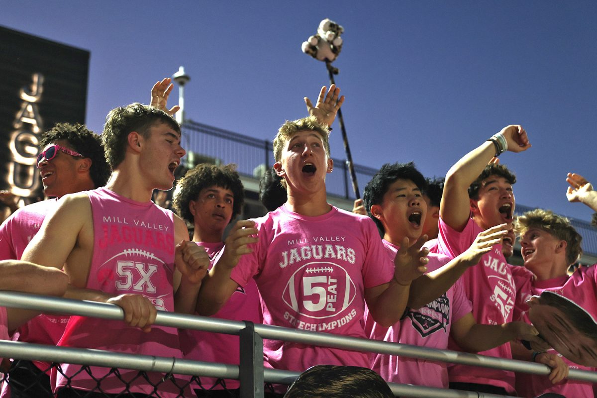With their hands up, seniors Hudson Powers and Ian Chern cheer on the football team. 