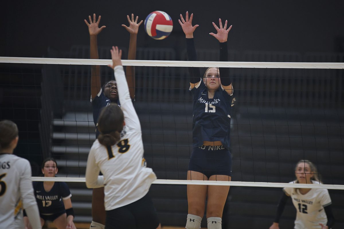 Hands reaching above the net, sophomore Josie Danielson attempts to block the opponents hit on Thursday, Oct 3.