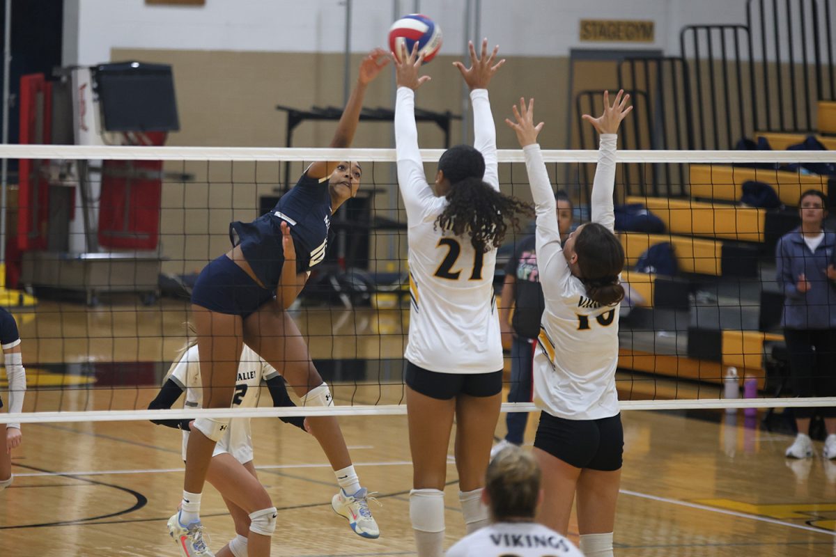 Reaching, Junior Leilah Perry hits the ball over the blockers hands Thursday, Oct 3.