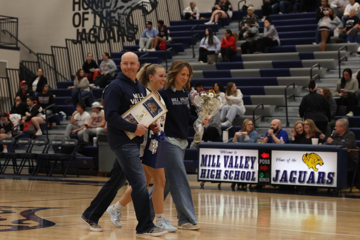 Alongside her parents, senior Josie Benson makes her way across the court. 