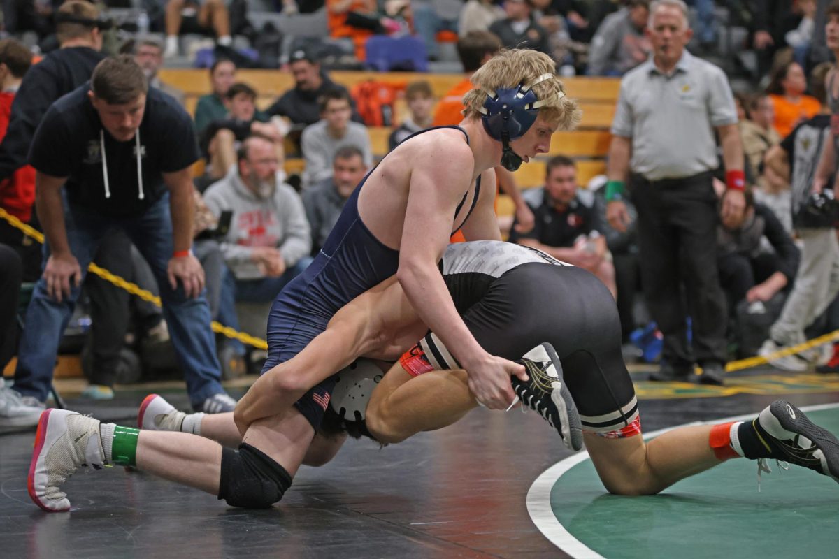 Holding his opponents ankle, senior Colton Bendure works to score a takedown. 