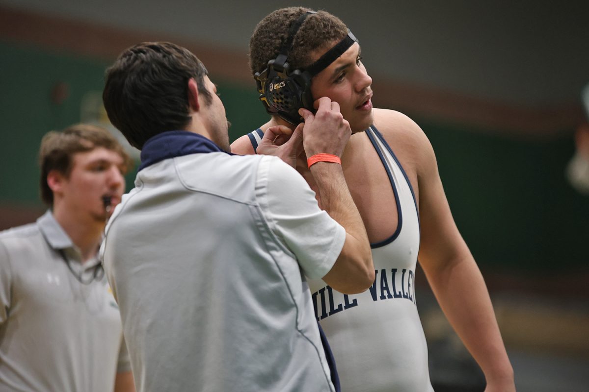 Wrestling coach Joey Lazor helps junior Lamarcus Barber with his head gear. 