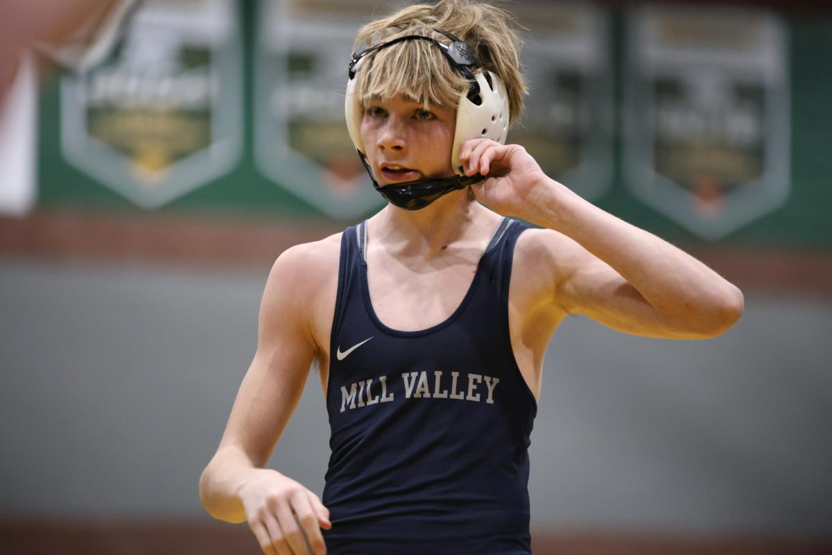 Freshman Charlie Supica reaches up to snap off his head gear. 