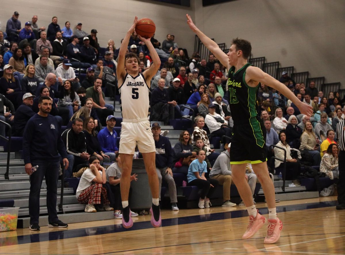 With his eyes on the rim, junior Reece Riedel shoots a three-point shot.