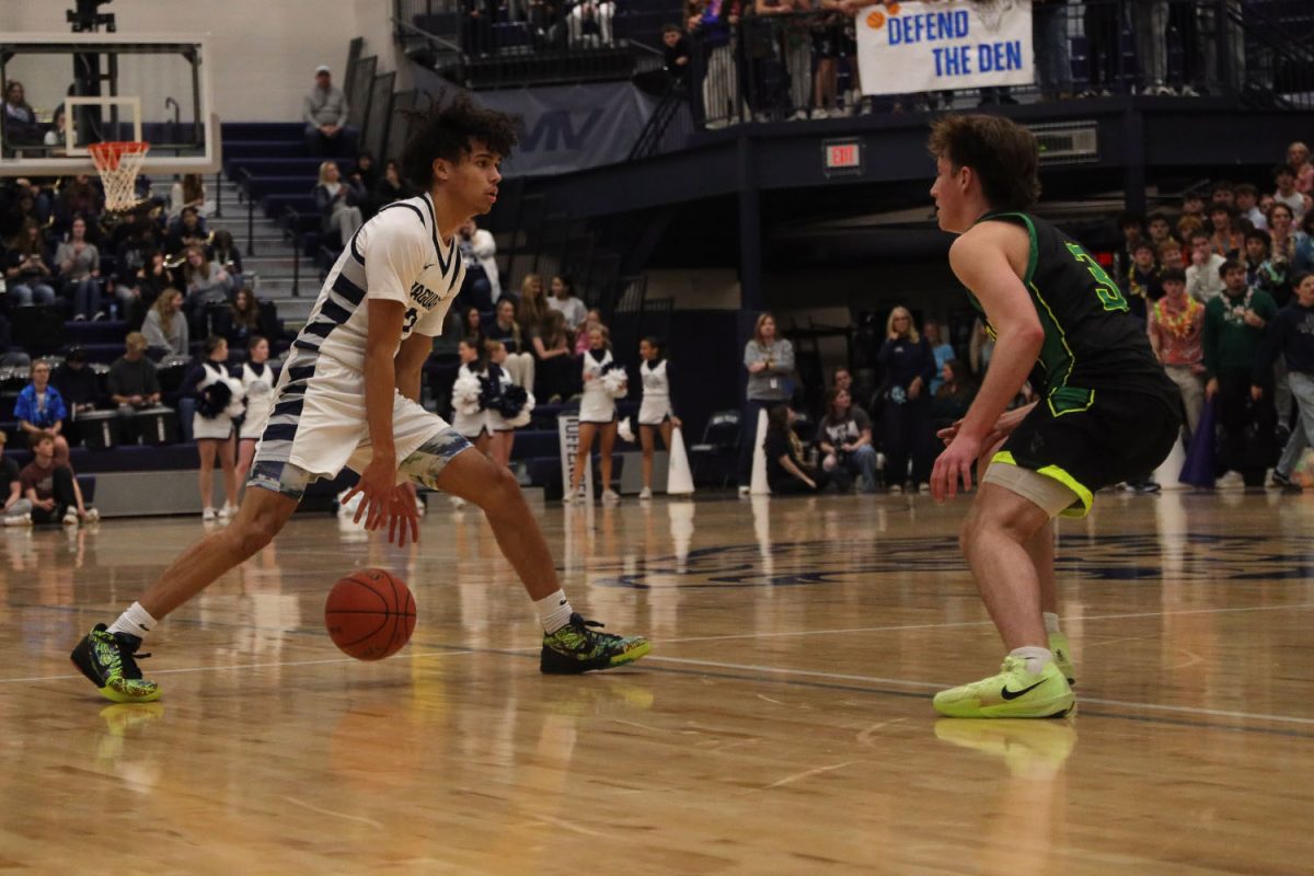 With his eyes on his opponent, junior Jakai Carter moves the ball up the court.