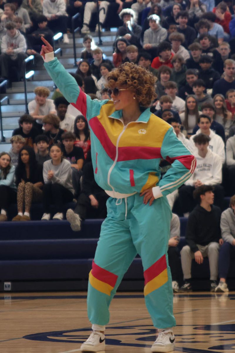 Dressed in a neon tracksuit, senior Josie Benson dances during the candidate introductions at the pep assembly.