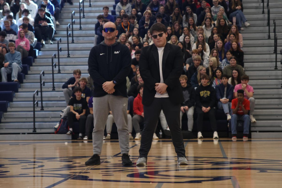 Looking out toward the crowd, senior Eric Penner and physical education teacher Jamie Resseguie pose at the end of their handshake.