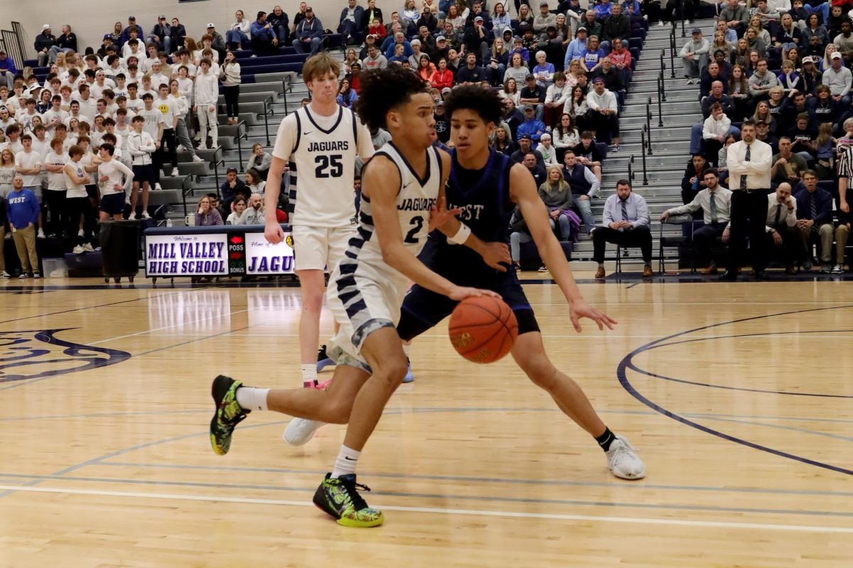 Avoiding the opponent, junior JaKhai Carter runs down the court.