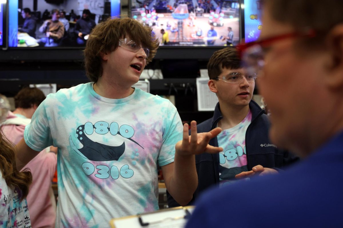 Along with his co-president, senior Carter Tollman discusses with the judges about the build process of their robots.