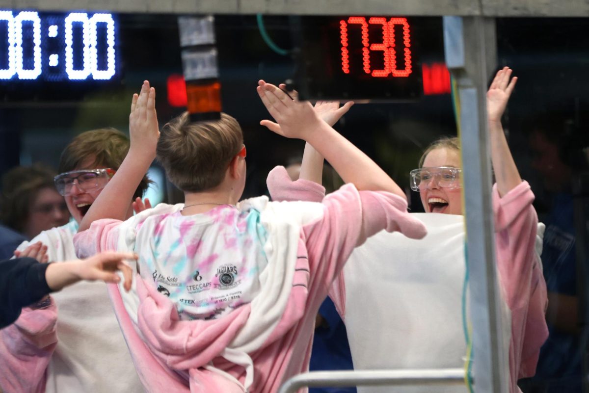 Grinning, freshman Tierney Gilmore high-fives her teammate after their alliance won their qualification round.