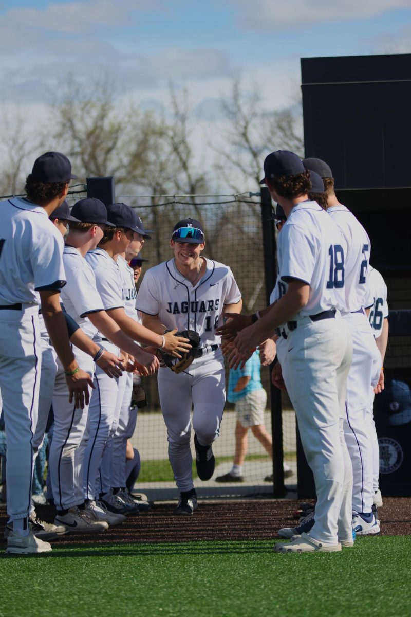 Smiling big, junior Beau Peterson prepares for high-fives from his teammates