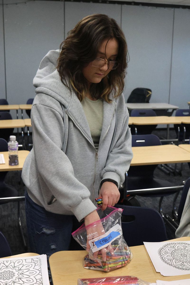 With her hand in the crayon bag, junior Mya Franco chooses a color for her coloring sheet.