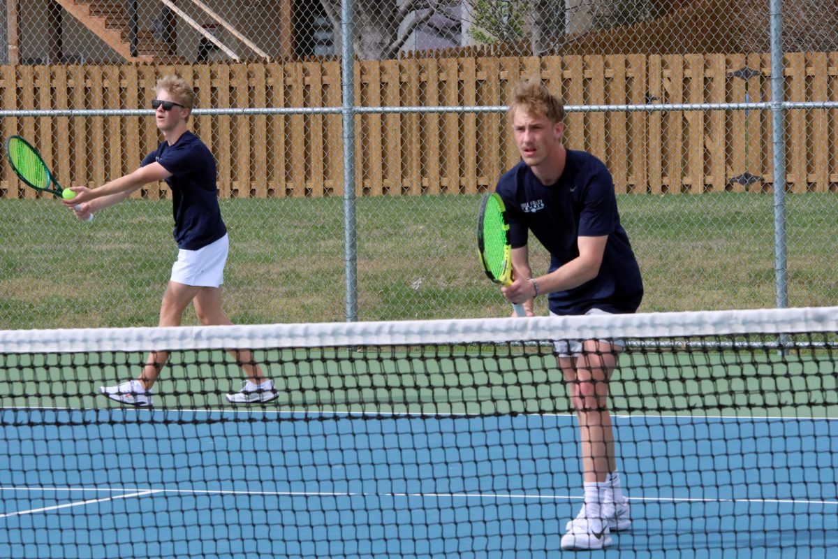 Junior Adam Bailey prepares to serve, Senior Cole Huffman anticipates the serve 