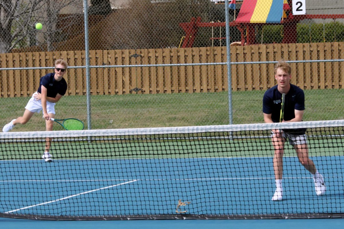 Junior Adam Bailey serves the ball while his teammate senior Cole Huffman awaits the return. 