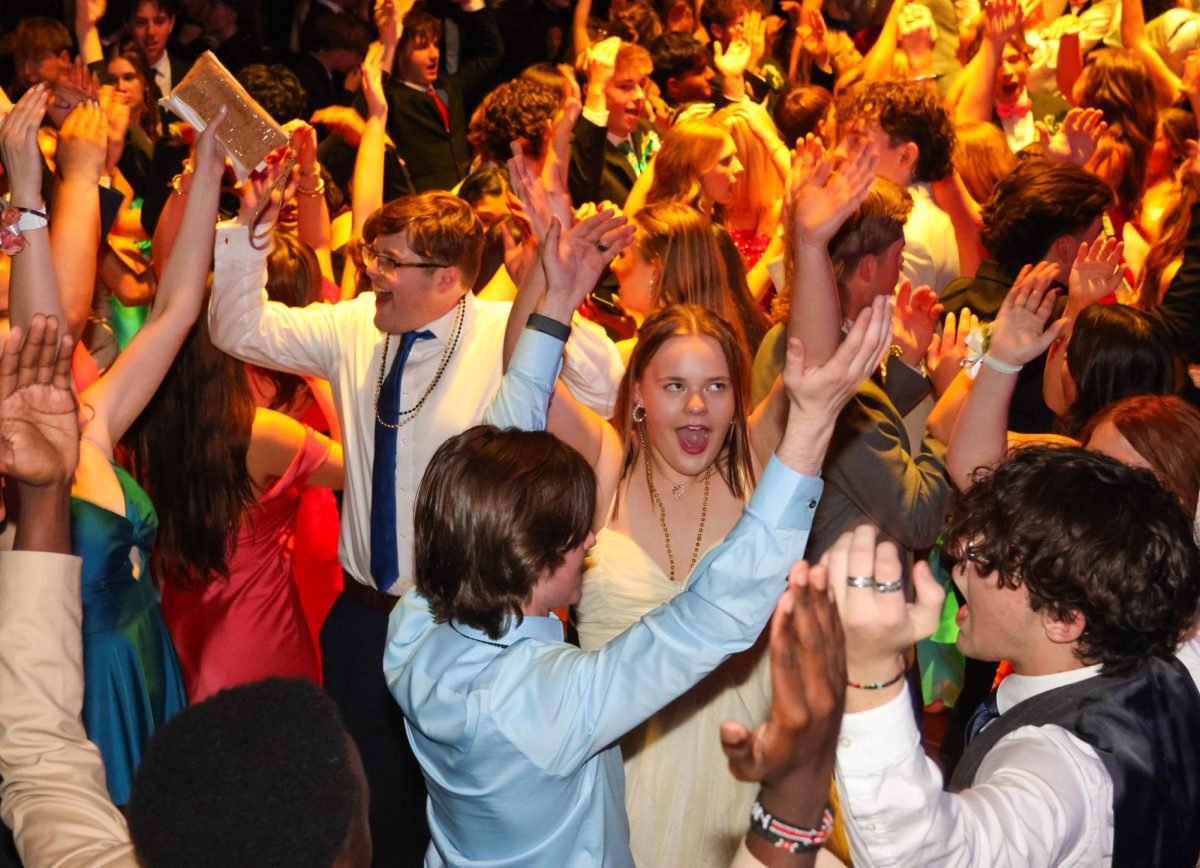 Singing the lyrics, junior Izzy Simms raises her hands in the air as she dances.
