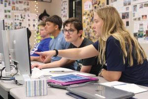 Learning to use Photoshop, freshman Xander Reynolds gets assistance from paraeducator Lilian Hollis on Wednesday, March 26. Recent special education withdrawals may halt the addition of new paraeducators. 
