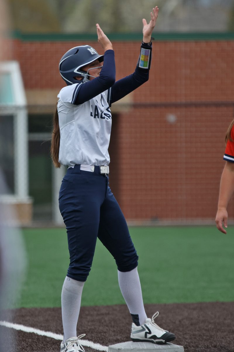 Hands in the air, junior Kinley Ruder cheers on her teammate’s hit.