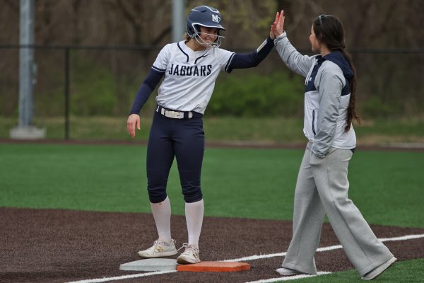 Standing at first, sophomore Peyton Heinrich high fives her coach after a line drive hit. 