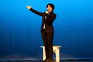 Putting his arms out in the air, junior Oliver Feiring hits a high note during his performance.